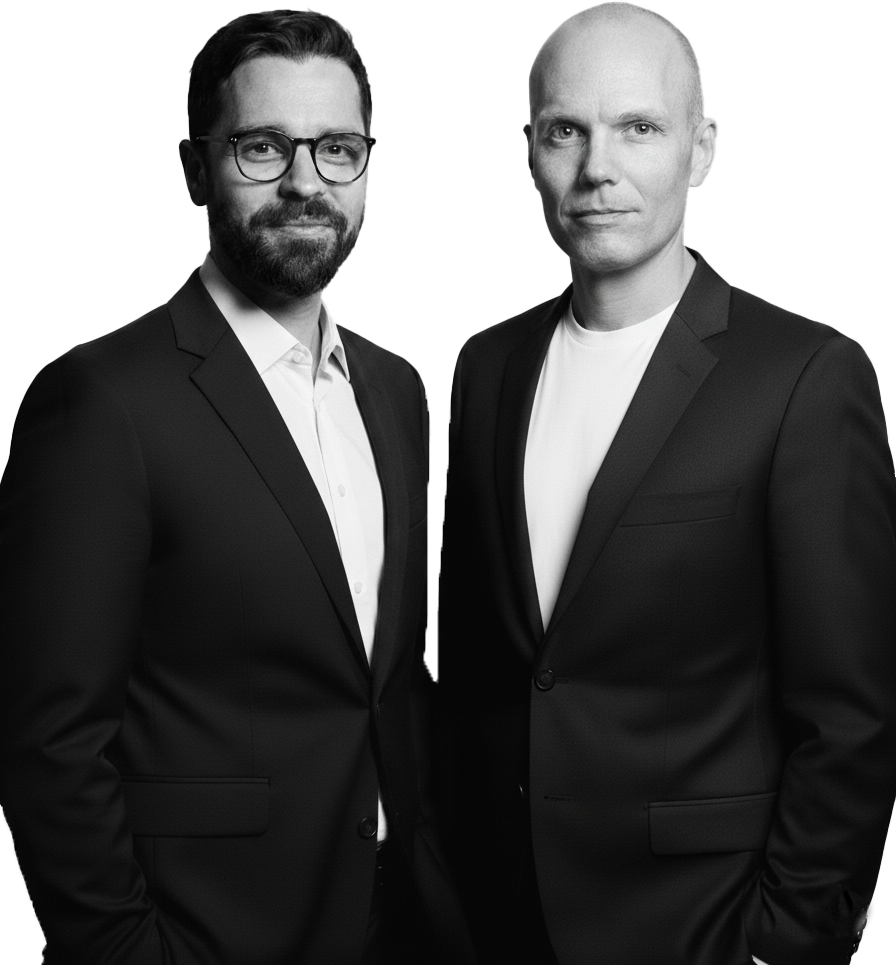 James and Mark Standing Suits A black and white photo of two men standing wearing suits,